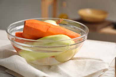 Photo of Different peeled vegetables in glass bowl on table indoors, closeup