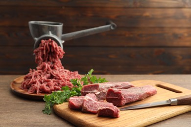 Manual meat grinder with beef and parsley on wooden table