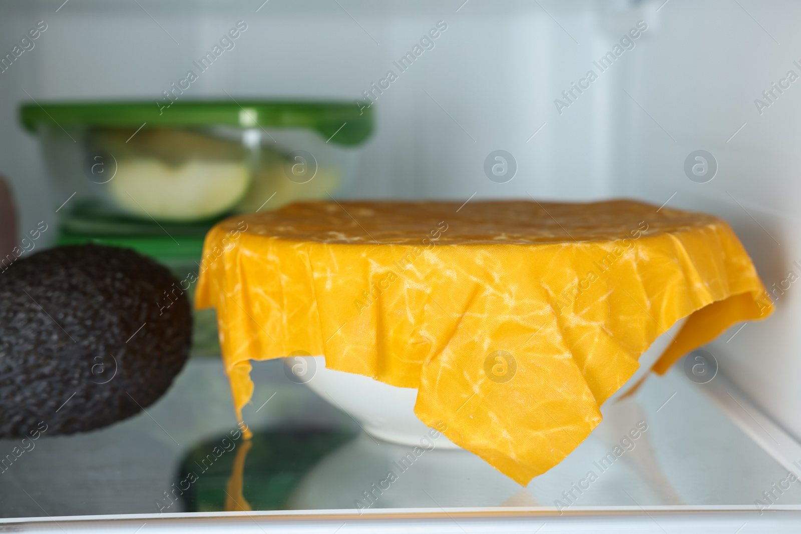 Photo of Products packed with beeswax food wrap on refrigerator shelf, closeup