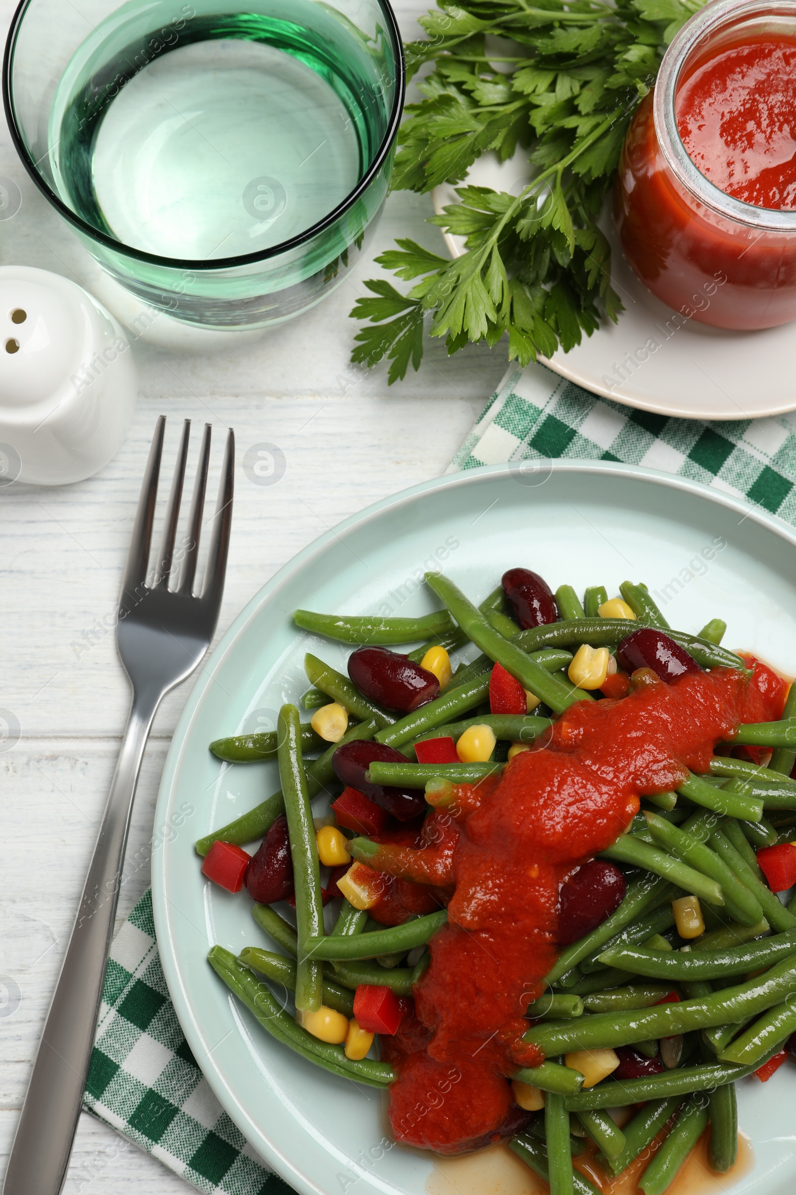 Photo of Delicious salad with green beans and tomato sauce served on white wooden table, flat lay