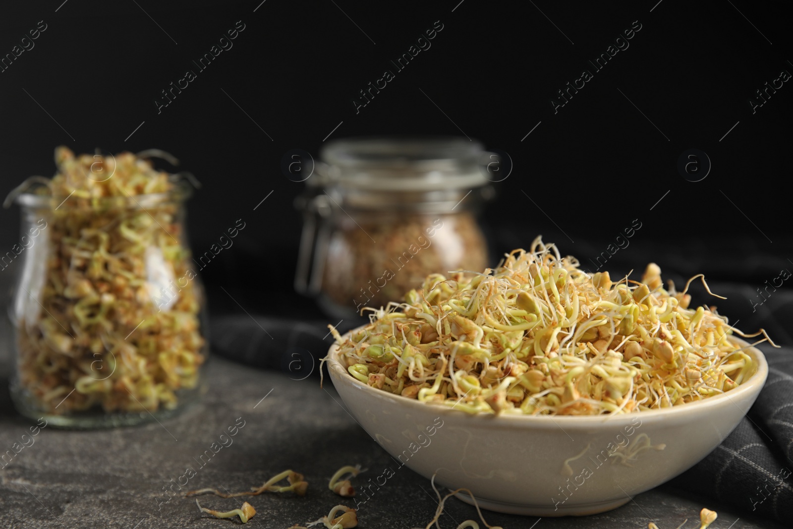 Photo of Bowl of sprouted green buckwheat on grey table