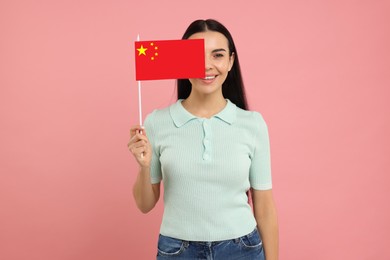 Happy young woman with flag of China on pink background