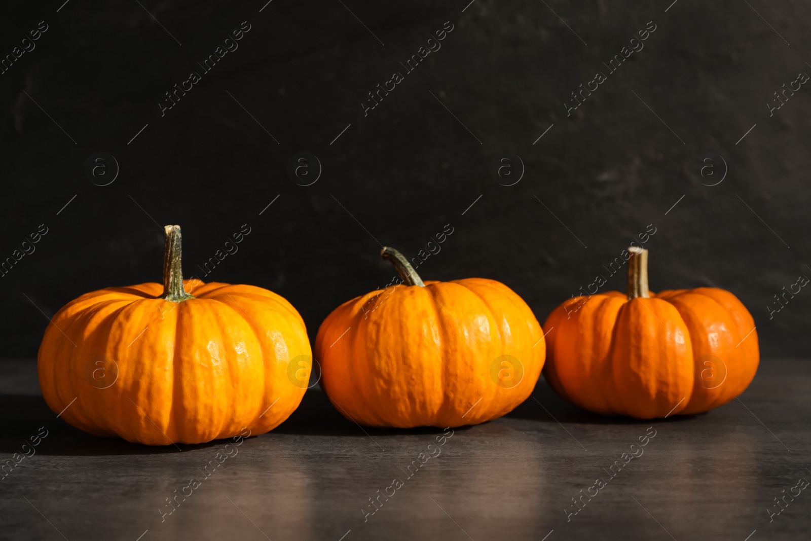 Photo of Fresh ripe orange pumpkins on black table