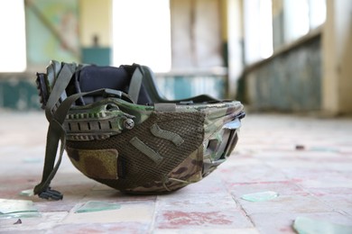 Photo of Military mission. Camouflage helmet on floor inside abandoned building, closeup