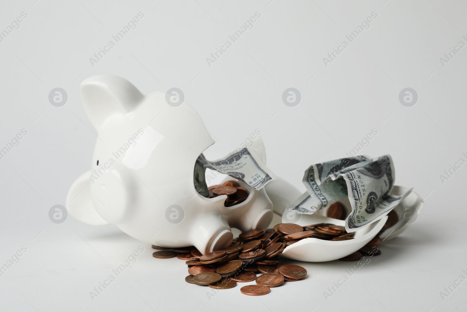 Photo of Broken piggy bank with coins and banknotes on light background