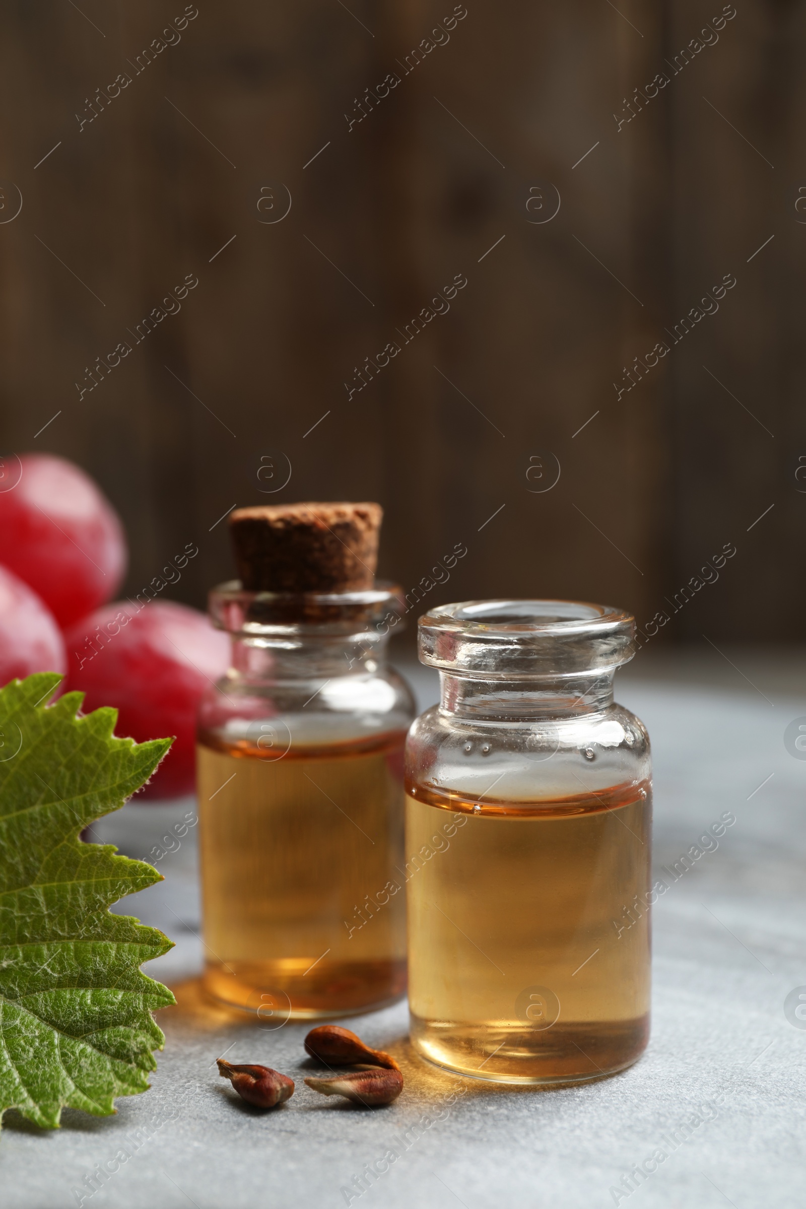 Photo of Bottles of natural grape seed oil on grey table. Organic cosmetic