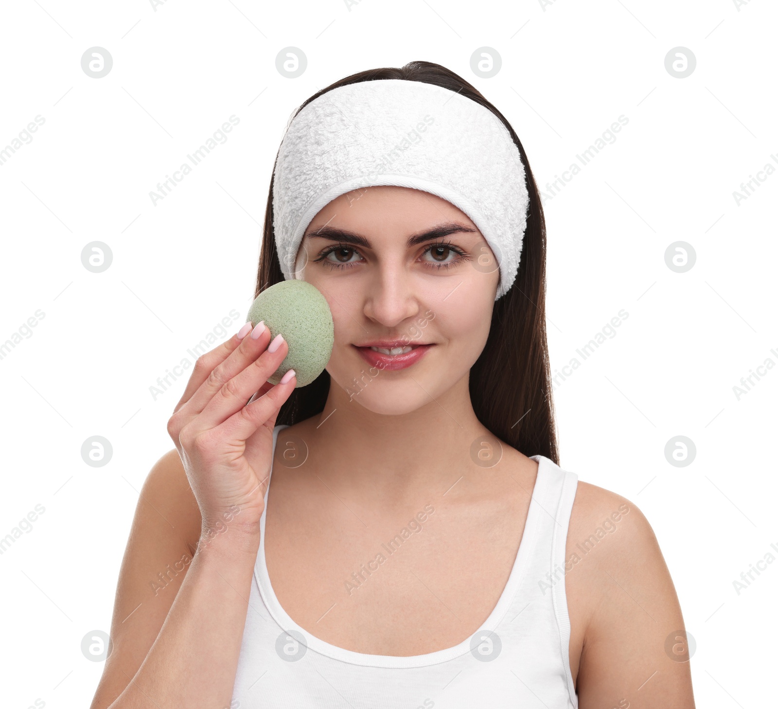 Photo of Young woman with headband washing her face using sponge on white background