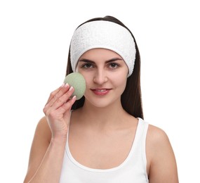 Photo of Young woman with headband washing her face using sponge on white background