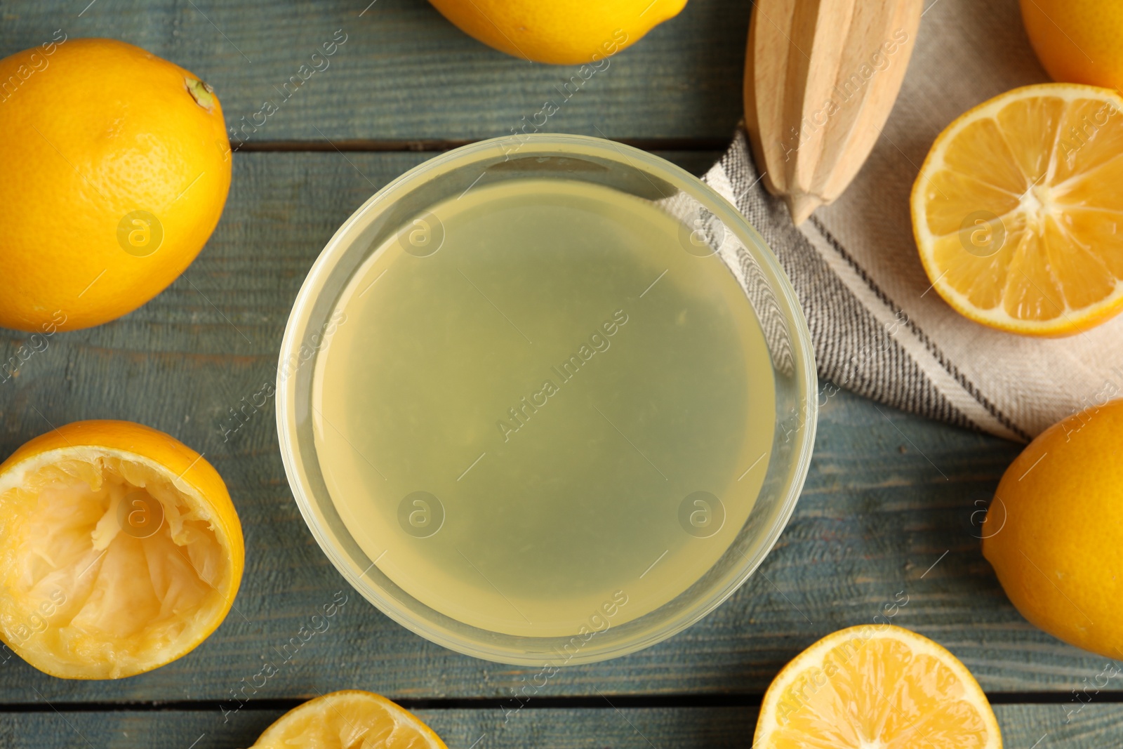 Photo of Freshly squeezed lemon juice on blue wooden table, flat lay