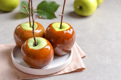 Plate with delicious green caramel apples on table