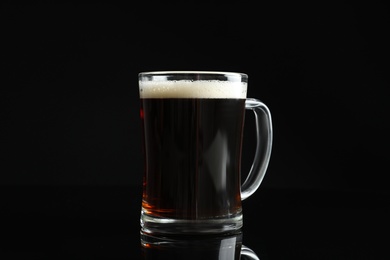 Photo of Glass mug of delicious kvass on black background