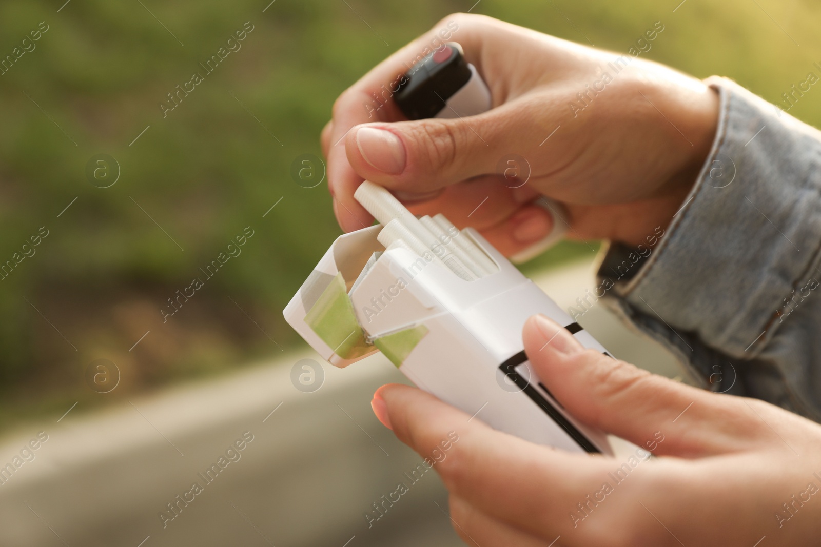 Photo of Woman taking cigarette out of pack outdoors, closeup