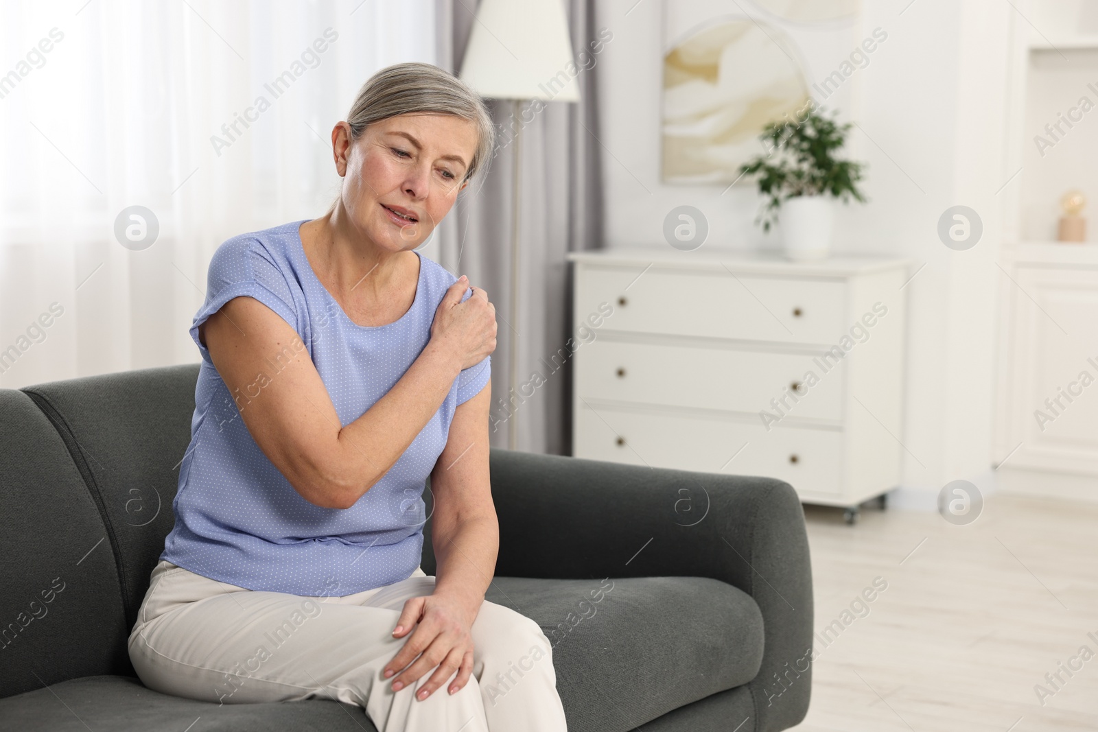 Photo of Arthritis symptoms. Woman suffering from pain in shoulder at home
