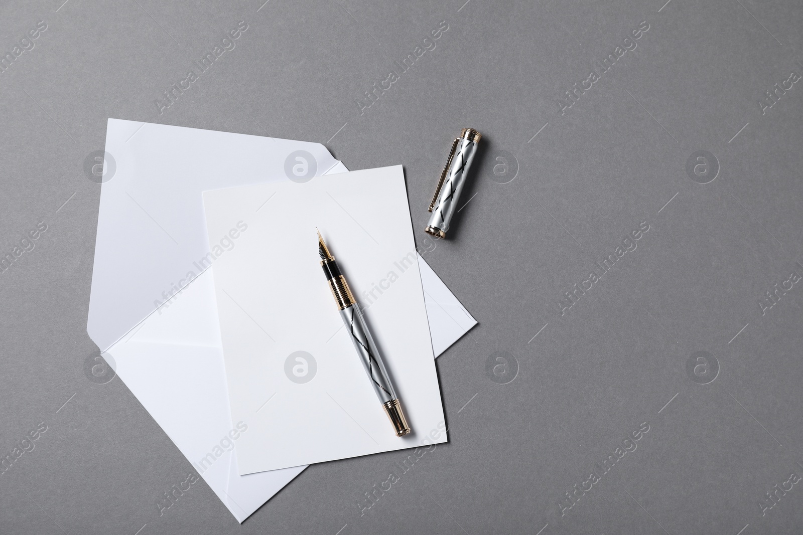 Photo of Blank sheet of paper, letter envelope and pen on grey background, top view. Space for text