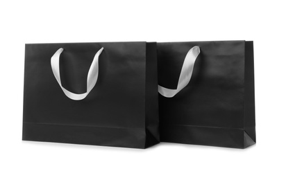 Photo of Paper shopping bags with ribbon handles on white background. Mockup for design