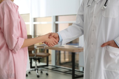 Doctor and patient shaking hands in clinic, closeup