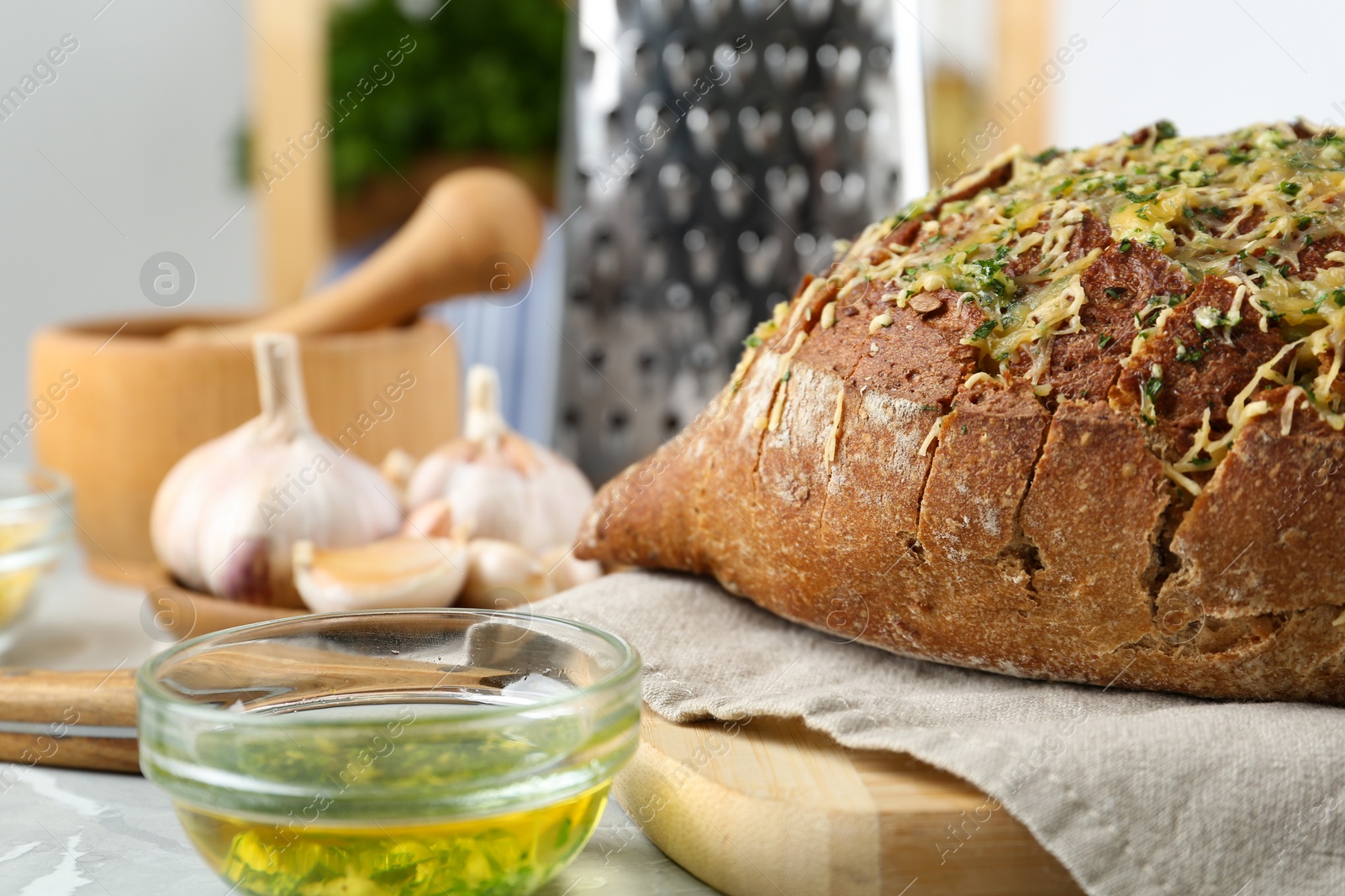 Photo of Tasty homemade garlic bread with cheese and herbs on light table