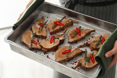 Woman holding baking tray with delicious roasted  ribs, closeup