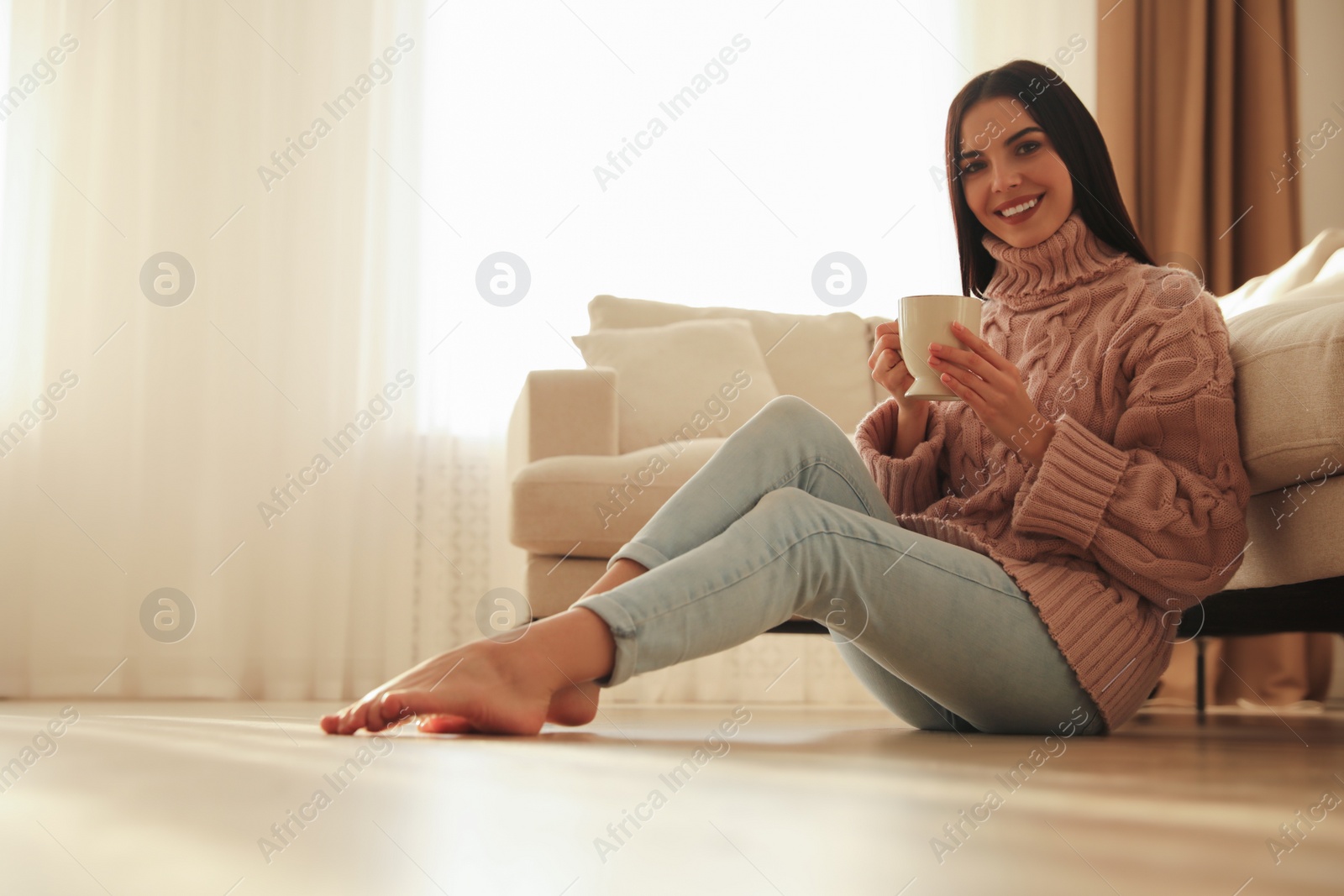 Photo of Woman sitting on warm floor in living room. Heating system