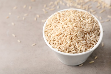 Uncooked brown rice in small bowl on table. Space for text