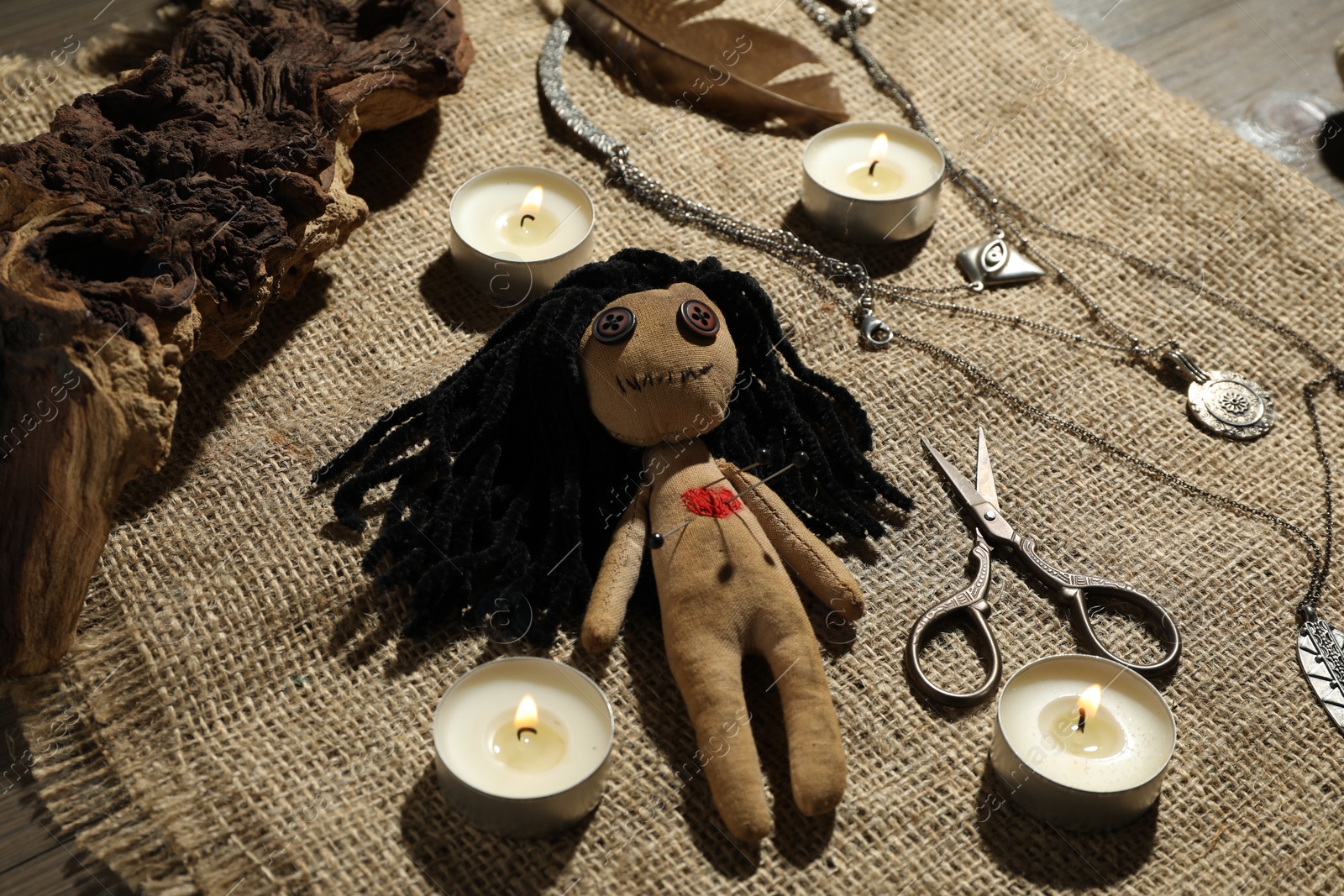 Photo of Voodoo doll with pins surrounded by ceremonial items on burlap fabric