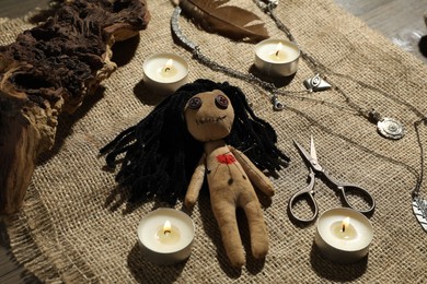 Voodoo doll with pins surrounded by ceremonial items on burlap fabric