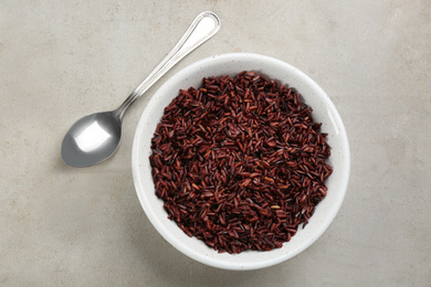 Tasty brown rice and spoon on light grey table, flat lay