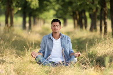 Photo of Man meditating in forest on sunny day