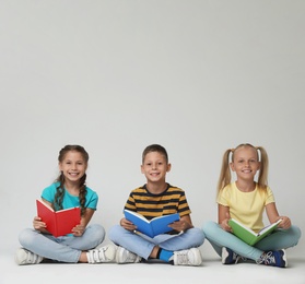 Photo of Little children reading books on grey background