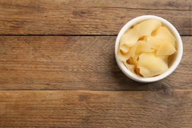 Photo of Pickled ginger in bowl on wooden table, top view. Space for text 