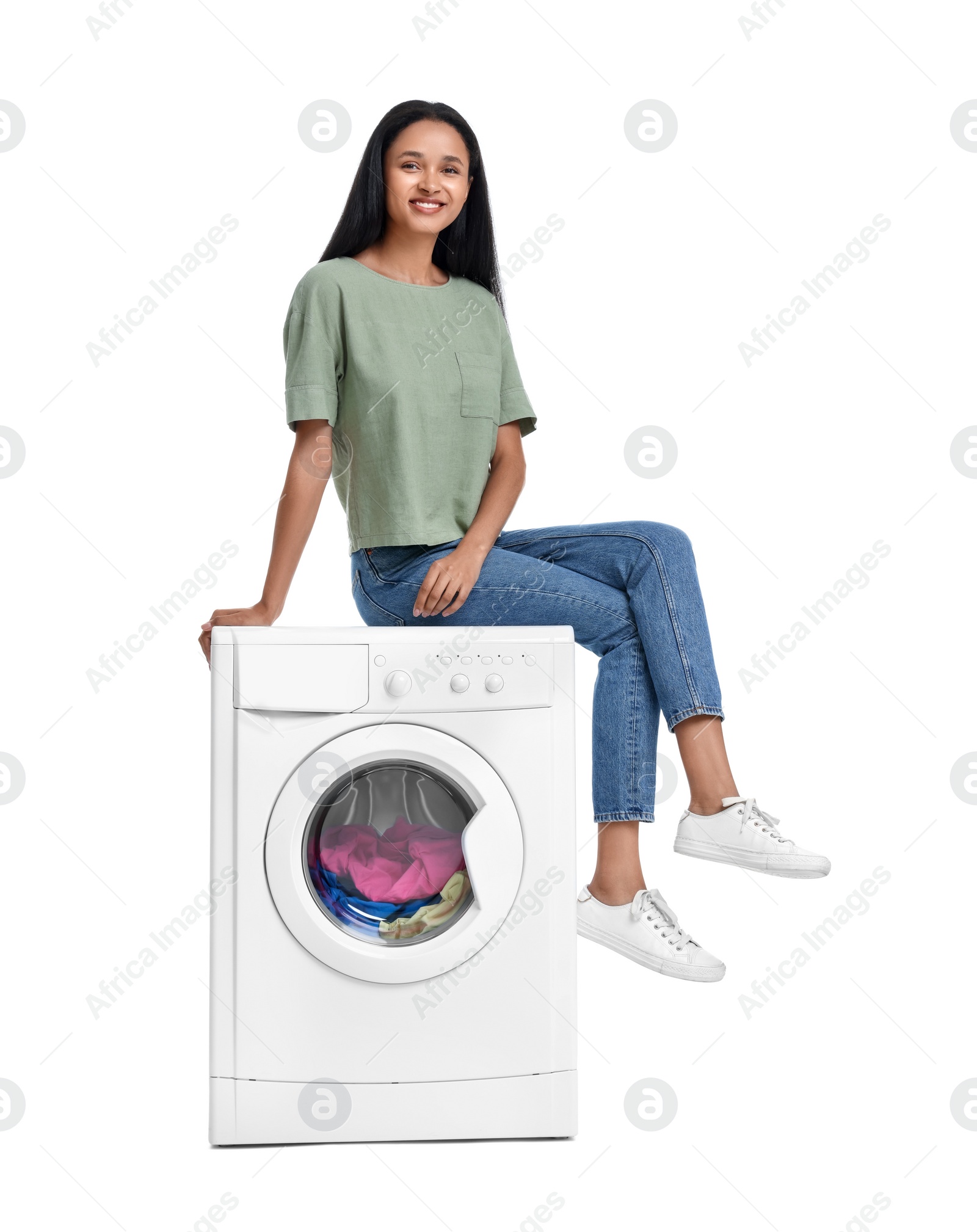 Photo of Beautiful woman sitting on washing machine with laundry against white background