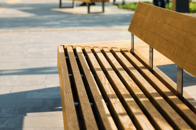 Photo of Wooden bench in city park on sunny morning, closeup