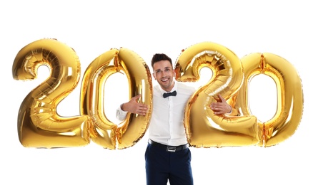 Happy young man with golden 2020 balloons on white background. New Year celebration