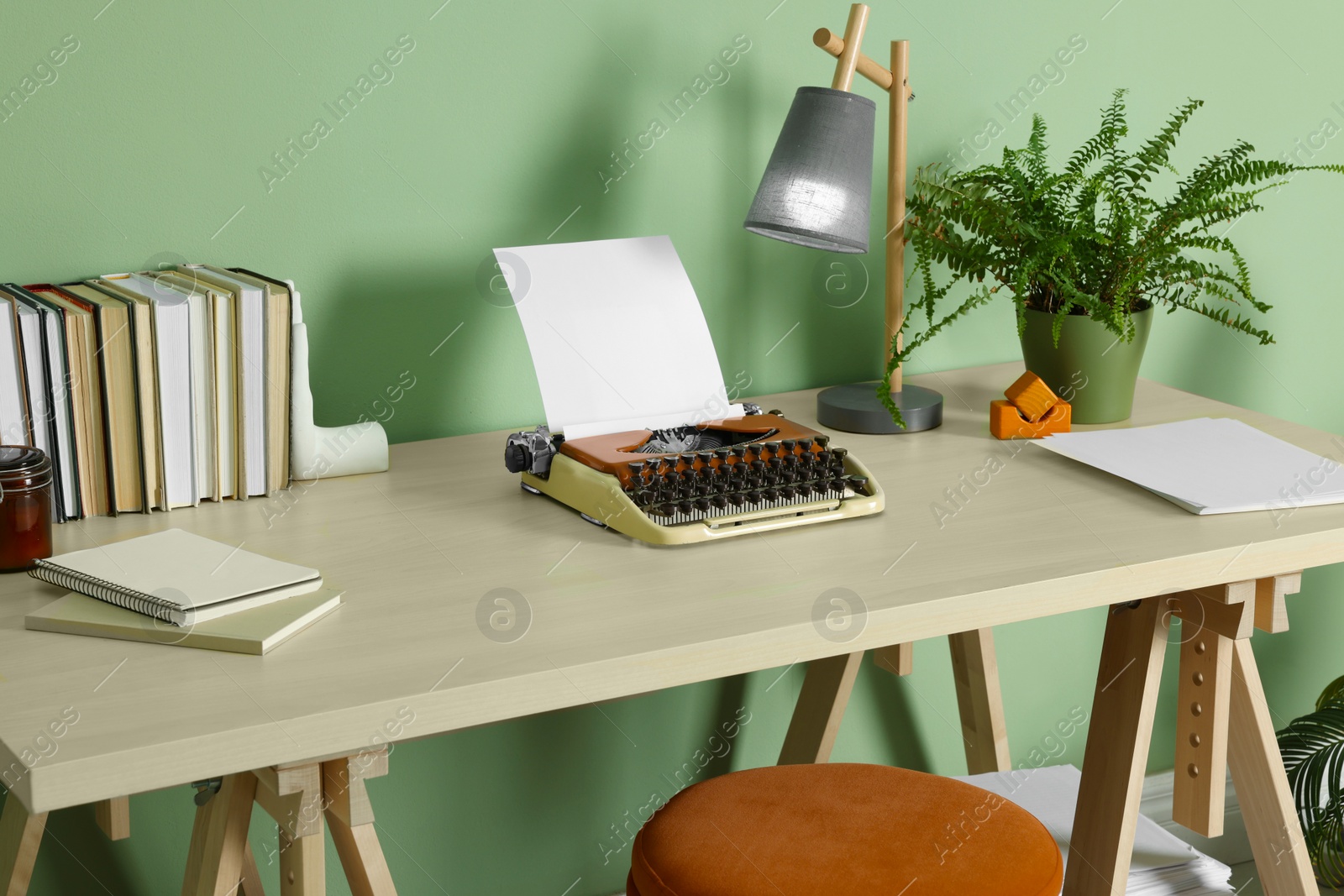 Photo of Writer's workplace with typewriter on wooden desk near pale green wall in room