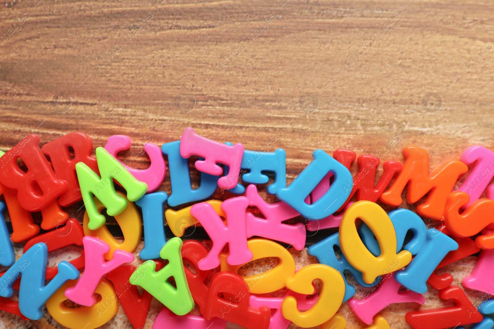 Photo of Colorful magnetic letters on wooden table, flat lay. Space for text