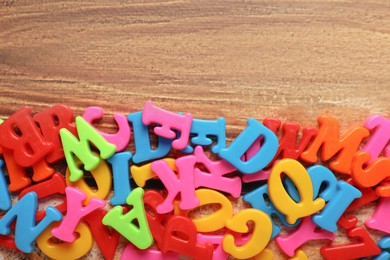 Colorful magnetic letters on wooden table, flat lay. Space for text