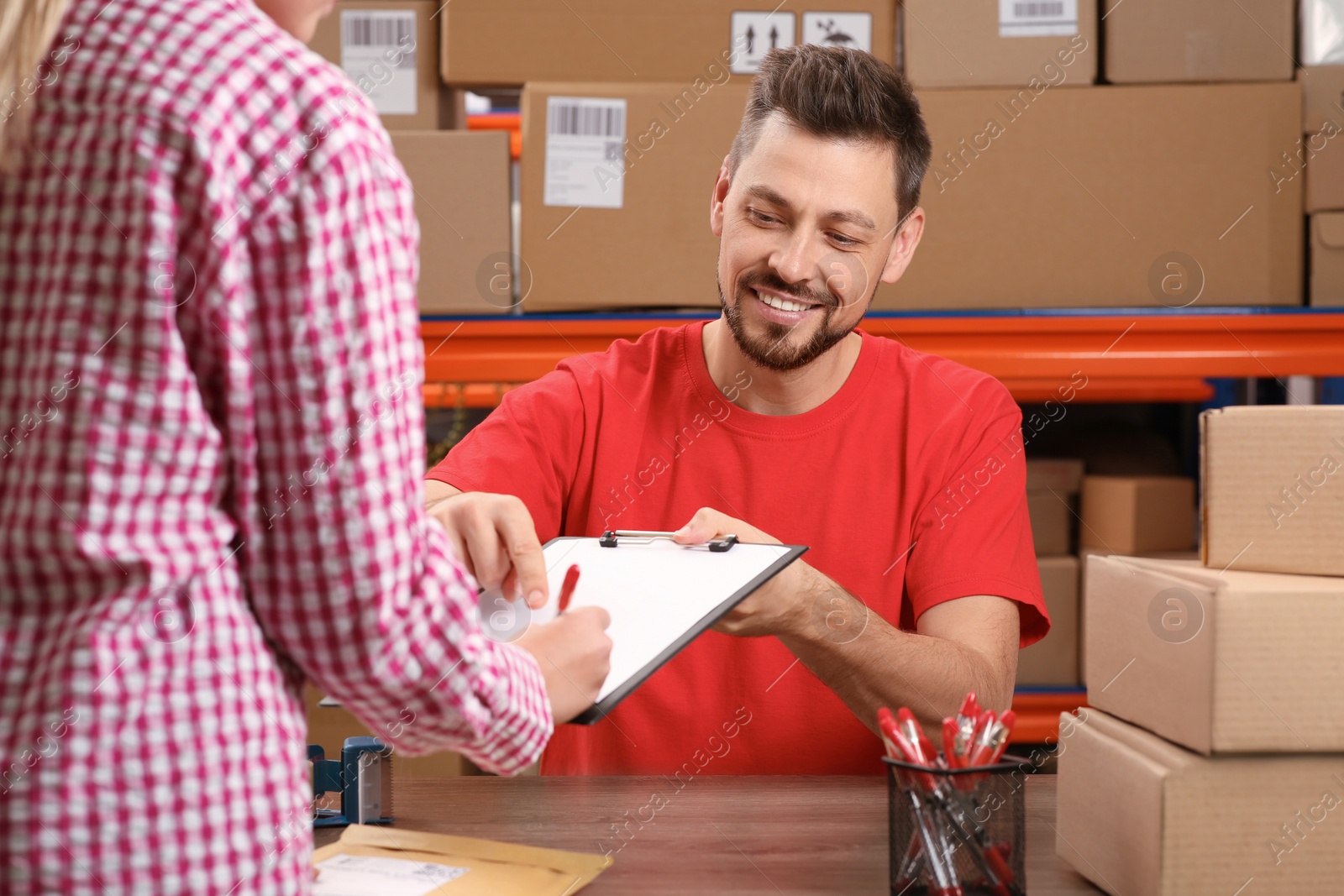 Photo of Woman signing papers for delivered parcel at post office