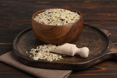 Photo of Dishware with raw unpolished rice on wooden table