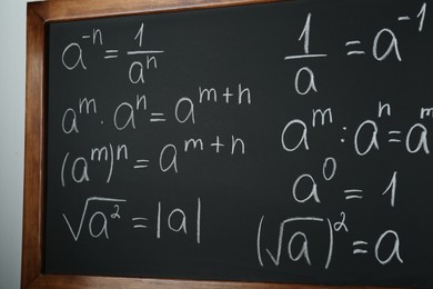 Chalkboard with many different math formulas on white wall, closeup