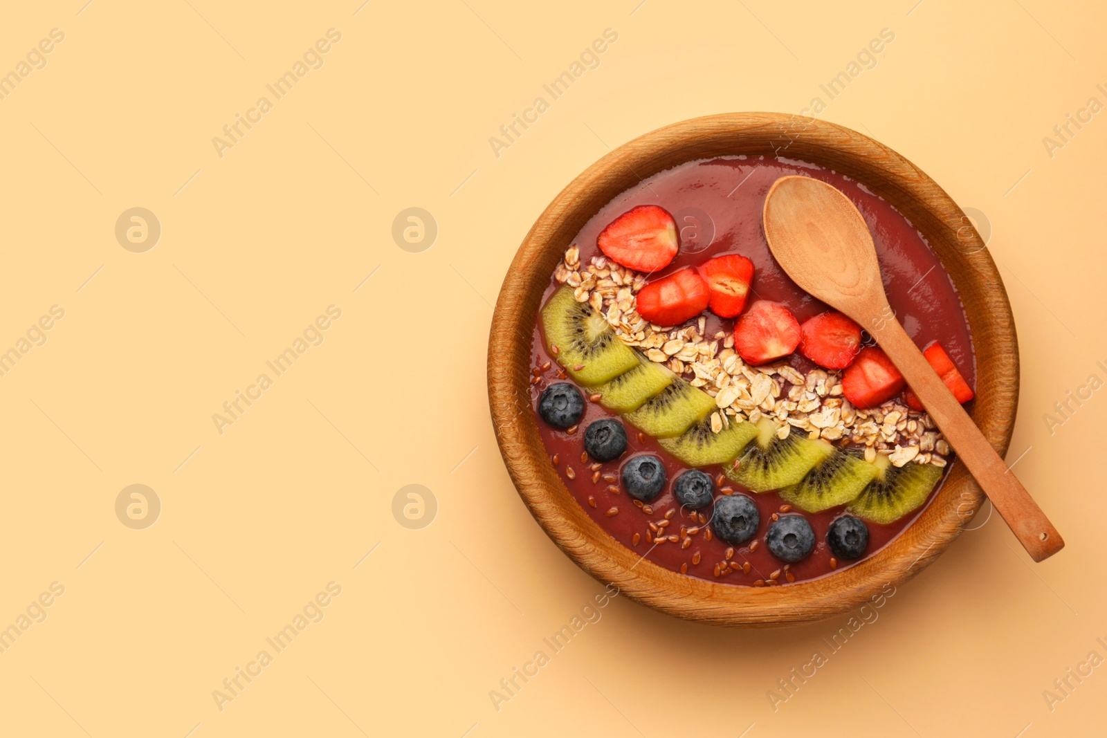 Photo of Bowl of delicious smoothie with fresh blueberries, strawberries, kiwi slices and oatmeal on color background, top view. Space for text