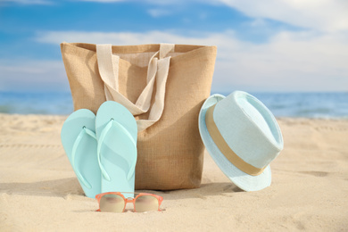 Different stylish beach objects on sand near sea