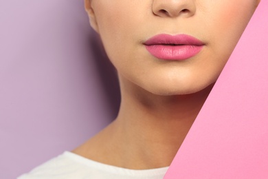 Young woman wearing beautiful lipstick on color background, closeup