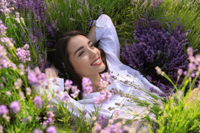 Photo of Young woman lying in lavender field on summer day