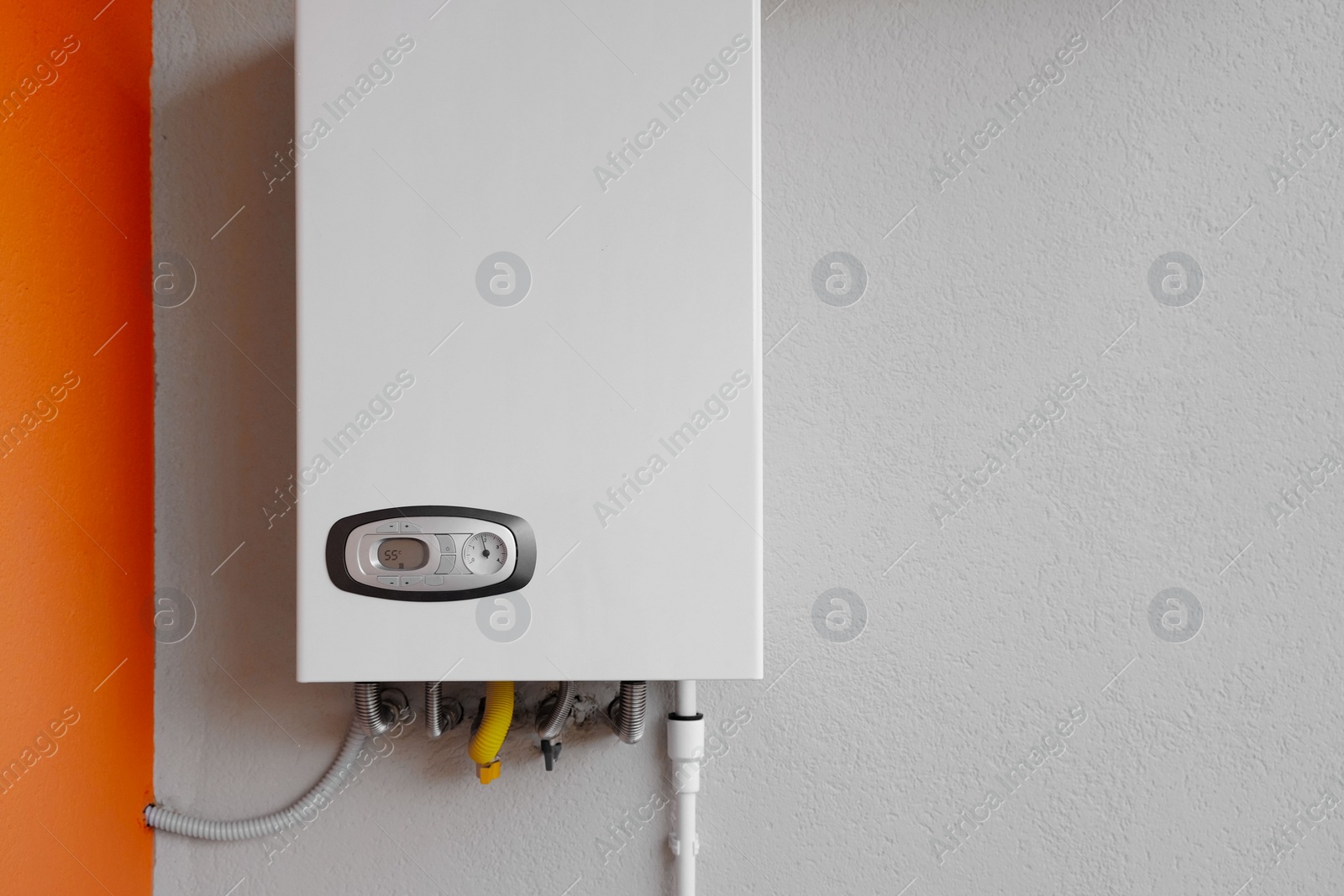 Photo of Gas boiler with temperature control indicator on white wall. Space for text