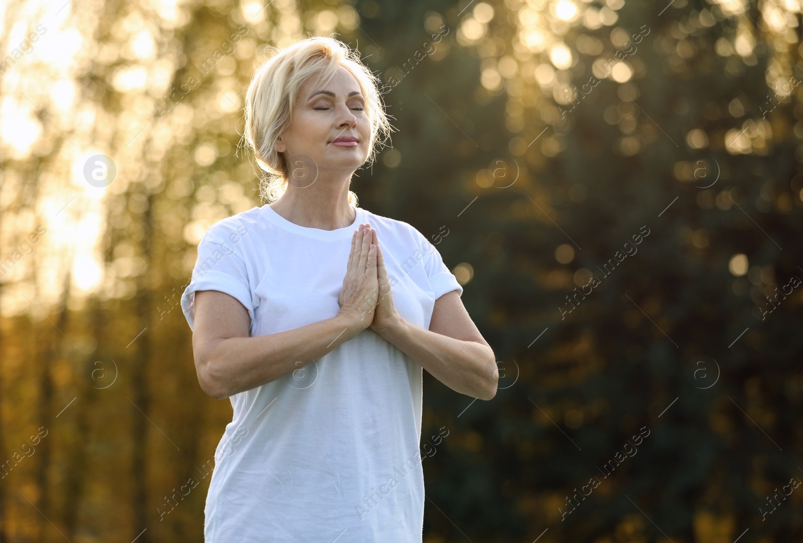 Image of Mature woman practicing yoga outdoors in morning