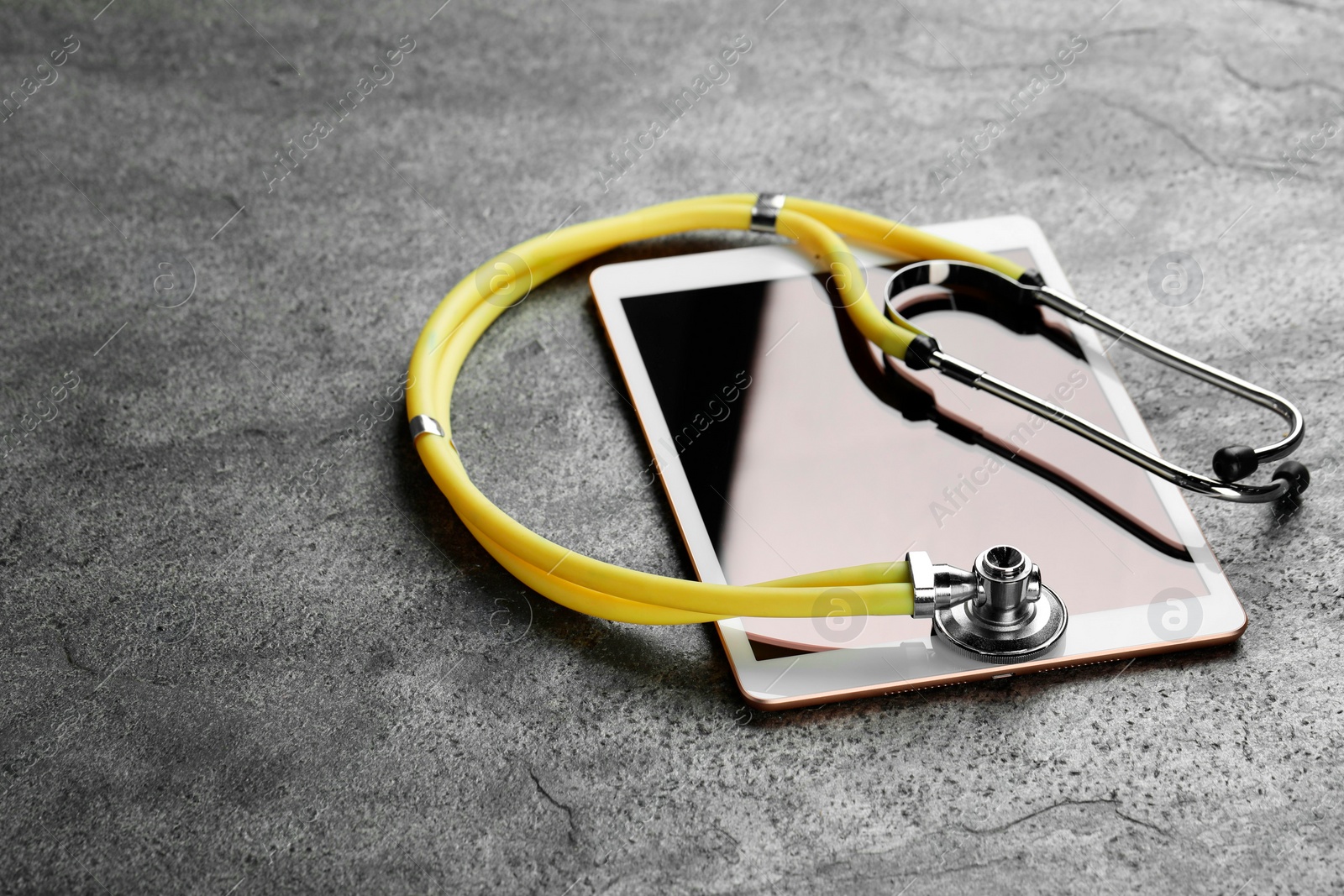 Photo of Modern tablet and stethoscope on grey table