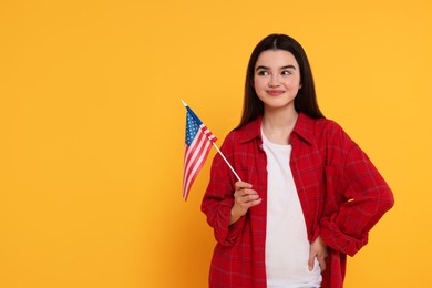 Photo of 4th of July - Independence Day of USA. Happy girl with American flag on yellow background, space for text