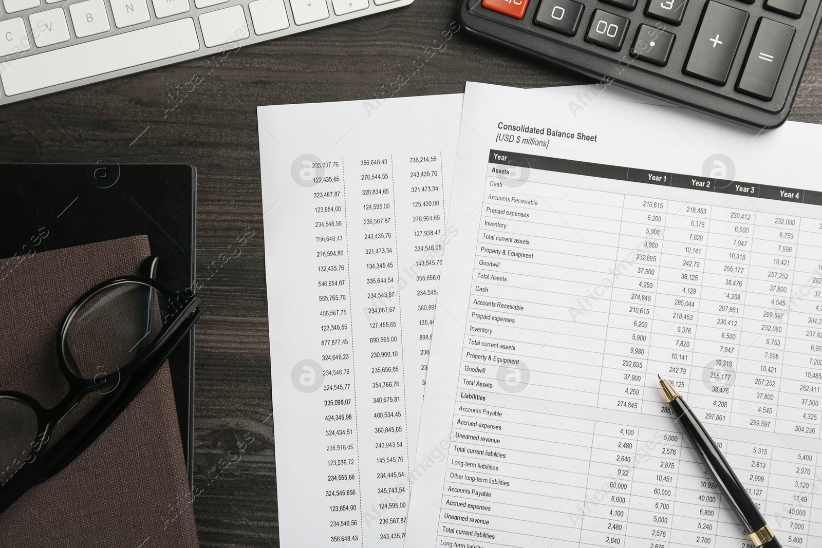 Photo of Accounting documents, glasses and stationery on wooden table, flat lay