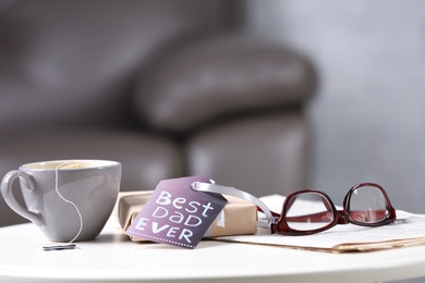 Cup, gift box and glasses on table. Father's day celebration