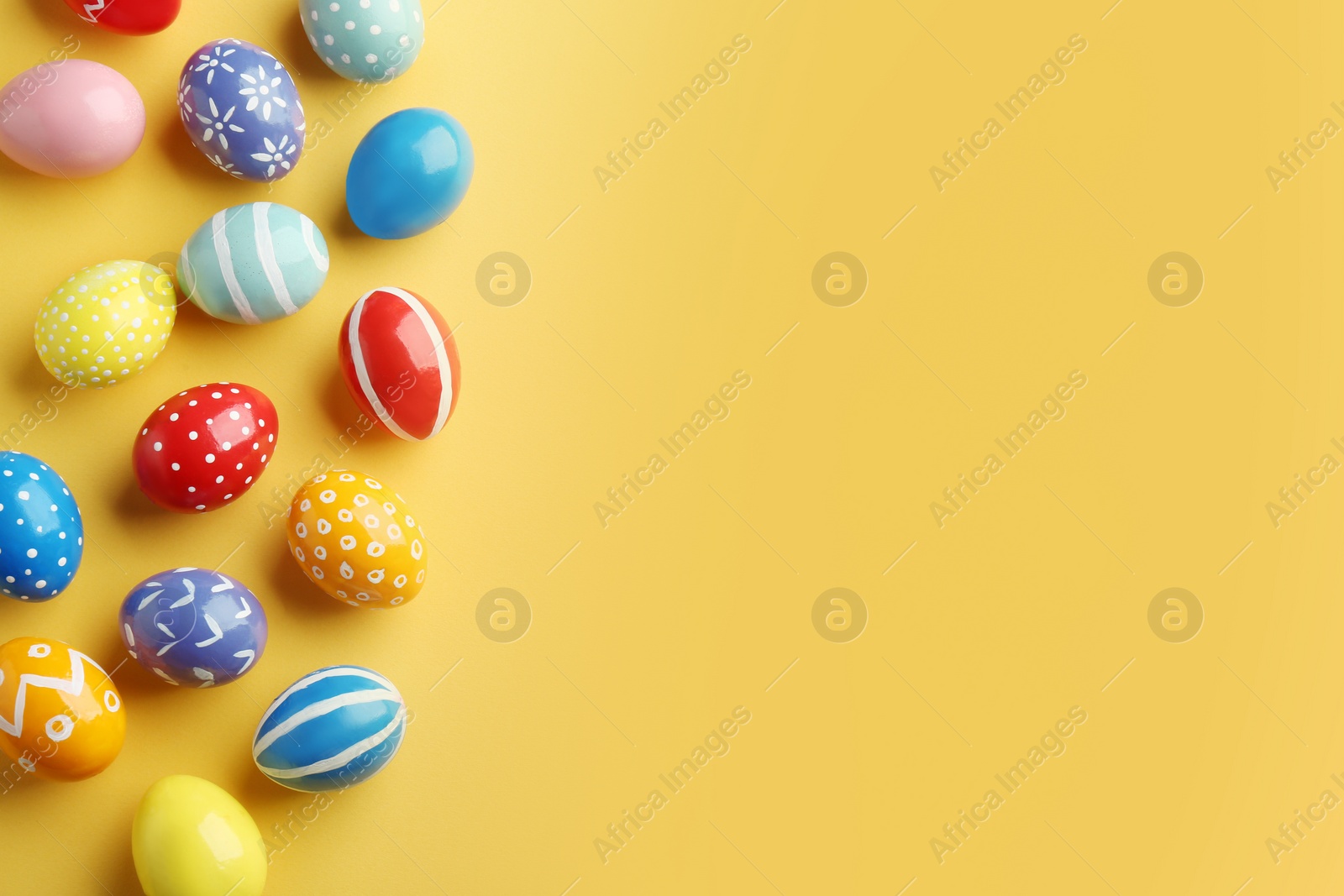 Photo of Flat lay composition of painted Easter eggs on color background, space for text